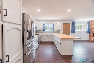 Kitchen with a peninsula, stainless steel appliances, recessed lighting, tasteful backsplash, and dark wood-style floors