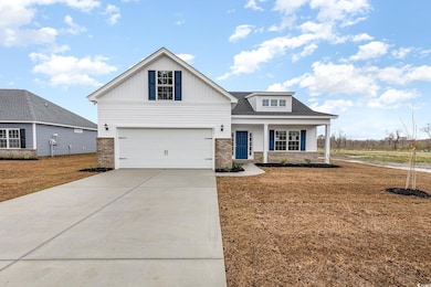 View of front of home with driveway, brick siding, a garage, a front yard, and a porch