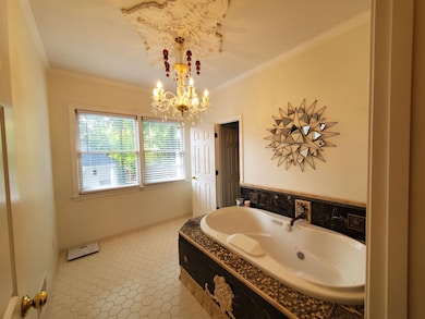 Bathroom with a jetted tub, a chandelier, crown molding, and baseboards