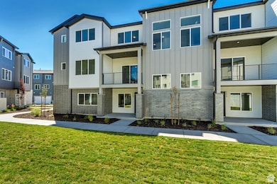 Back of house with board and batten siding, brick siding, a yard, and a balcony