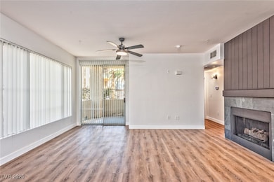 Unfurnished living room with a fireplace, light wood-style flooring, and a ceiling fan