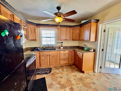 Kitchen featuring freestanding refrigerator, stainless steel electric range oven, stone finish floors, open shelves, and dark stone counters