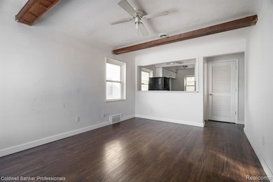 Unfurnished room with a textured ceiling, beam ceiling, dark wood-style flooring, and ceiling fan