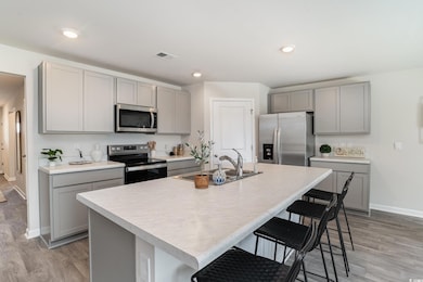 Kitchen featuring appliances with stainless steel finishes, gray cabinets, a kitchen breakfast bar, light wood-type flooring, and recessed lighting