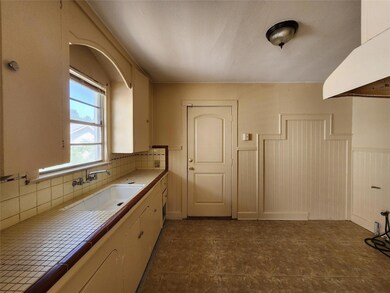 Kitchen with sink, backsplash, and dark tile floor