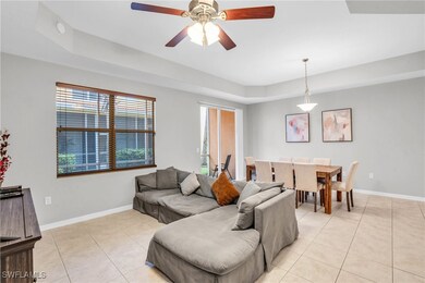 Tiled living room with ceiling fan and a tray ceil