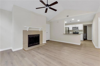 Unfurnished living room featuring ceiling fan, light wood-type flooring, a fireplace, high vaulted ceiling, and recessed lighting
