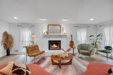 Living area featuring a fireplace, light wood-style flooring, recessed lighting, and an abundance of floor to ceiling windows.