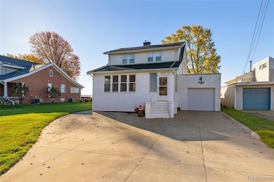 View of front of house featuring driveway, a chimney, and a front lawn