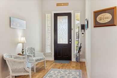 Every detail in this home reflects careful ownership. The entryway includes a dark wood front door with decorative glass and tall windows on each side.