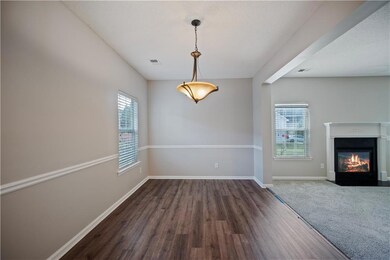 Unfurnished dining area featuring dark wood-style flooring, baseboards, and a fireplace with flush hearth