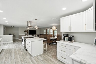 Kitchen featuring white cabinets, recessed lighting, hanging light fixtures, range with electric cooktop, and light stone counters