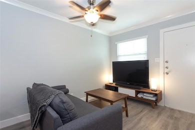 Living area with ornamental molding, light wood f
