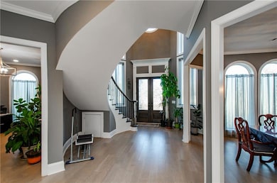Foyer featuring wood finished floors, french doors, crown molding, and stairs