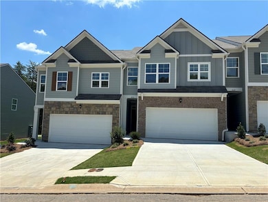 View of front of property featuring concrete driveway, an attached garage, board and batten siding, and stone siding