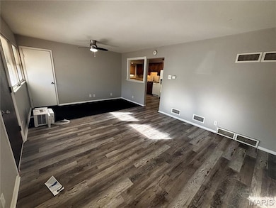 Spare room with dark wood-type flooring and a ceiling fan