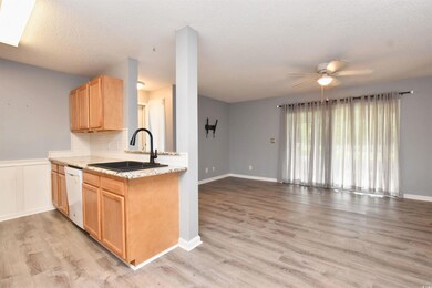 Kitchen featuring decorative backsplash, open floor plan, light brown cabinetry, ceiling fan, and a textured ceiling