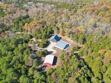 Aerial view of property and surrounding area featuring a heavily wooded area