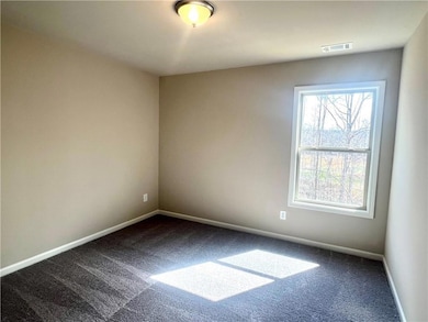 Spare room featuring dark colored carpet, visible 