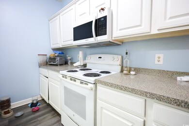 Kitchen with dark wood-type flooring, white cabine