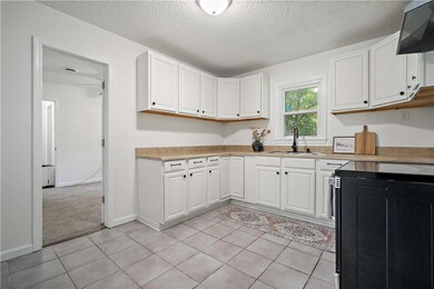 Kitchen with dishwasher, white cabinets, a textured ceiling, light countertops, and light tile patterned floors