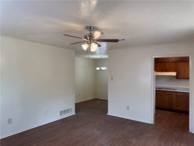 Empty room featuring a ceiling fan, dark wood-styl