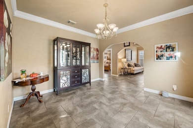 Foyer entrance featuring crown molding, arched walkways, and a chandelier