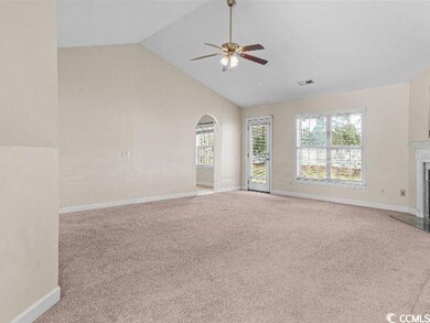 Unfurnished living room featuring light colored carpet, arched walkways, high vaulted ceiling, a fireplace with flush hearth, and a ceiling fan