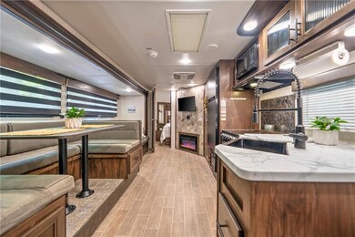 Kitchen featuring a large fireplace, light wood-type flooring, light stone counters, and brown cabinets