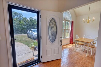 Foyer entrance with a chandelier, light wood finished floors, and vaulted ceiling