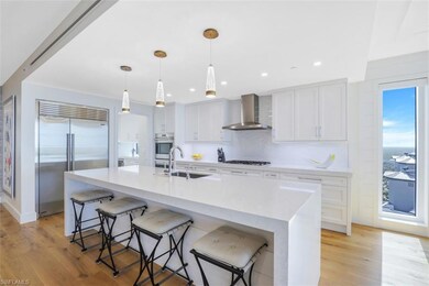 Kitchen featuring stainless steel appliances, white cabinetry, a kitchen bar, light countertops, and light wood finished floors