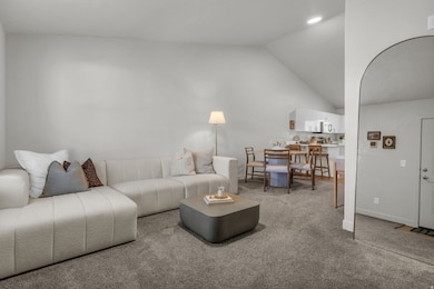 Living room with carpet flooring, vaulted ceiling, and arched walkways