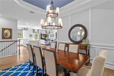 Dining space with a tray ceiling, crown molding, a chandelier, and light wood finished floors