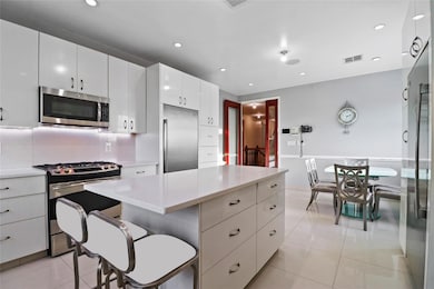 Kitchen featuring stainless steel appliances, light tile patterned floors, a center island, white cabinets, and recessed lighting