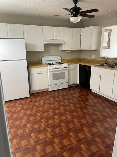 Kitchen with fridge, gas range gas stove, white cabinets, a textured ceiling, and dishwasher