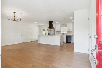 Unfurnished living room with a chandelier, light wood-style flooring, recessed lighting, and a textured ceiling