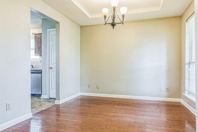 Spare room featuring wood-type flooring, a chandelier, a tray ceiling, and baseboards