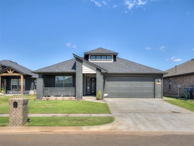 View of front facade with roof with shingles, brick siding, a front yard, and driveway
