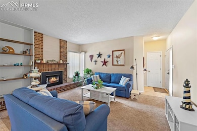 Carpeted living area featuring a fireplace and a textured ceiling