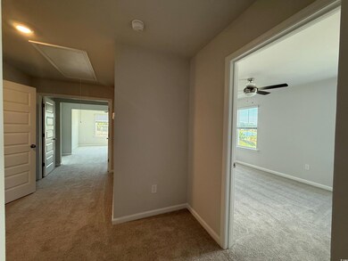 Hall with baseboards, carpet, and attic access
