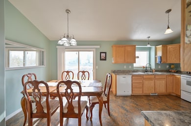 Kitchen featuring white appliances, a chandelier, stone finish floors, pendant lighting, and light brown cabinetry