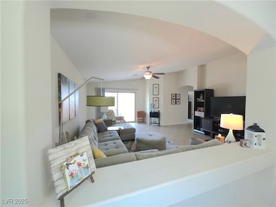 Living room with arched walkways, light tile patterned floors, and ceiling fan