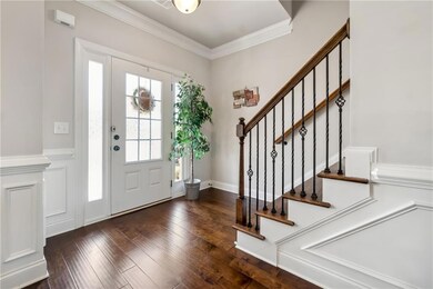 Foyer with dark wood-style floors, stairway, and ornamental molding
