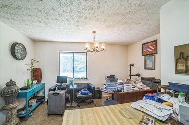 Carpeted home office with a chandelier and a textured ceiling