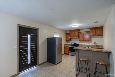 Kitchen featuring a breakfast bar, appliances with stainless steel finishes, a peninsula, brown cabinetry, and dark stone countertops