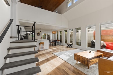 Living area with light wood-type flooring, a high ceiling, stairs, wood ceiling, and ceiling fan