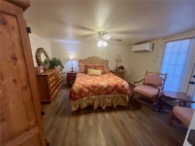 Primary bedroom with ceiling fan, and a wall mounted air conditioner