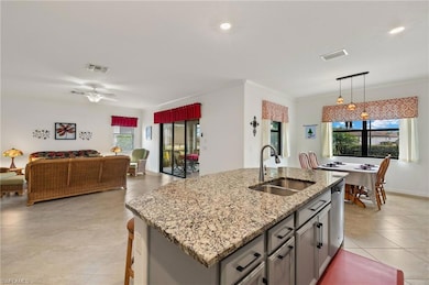 Kitchen with pendant light fixtures, a granite island with sink, stainless steel dishwasher, and granite countertops
