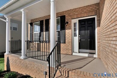 View of exterior entry with covered porch and brick siding