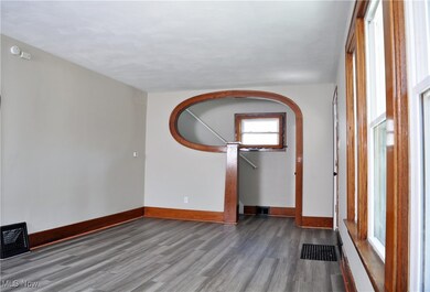 Unfurnished room with wood finished floors and arched walkways